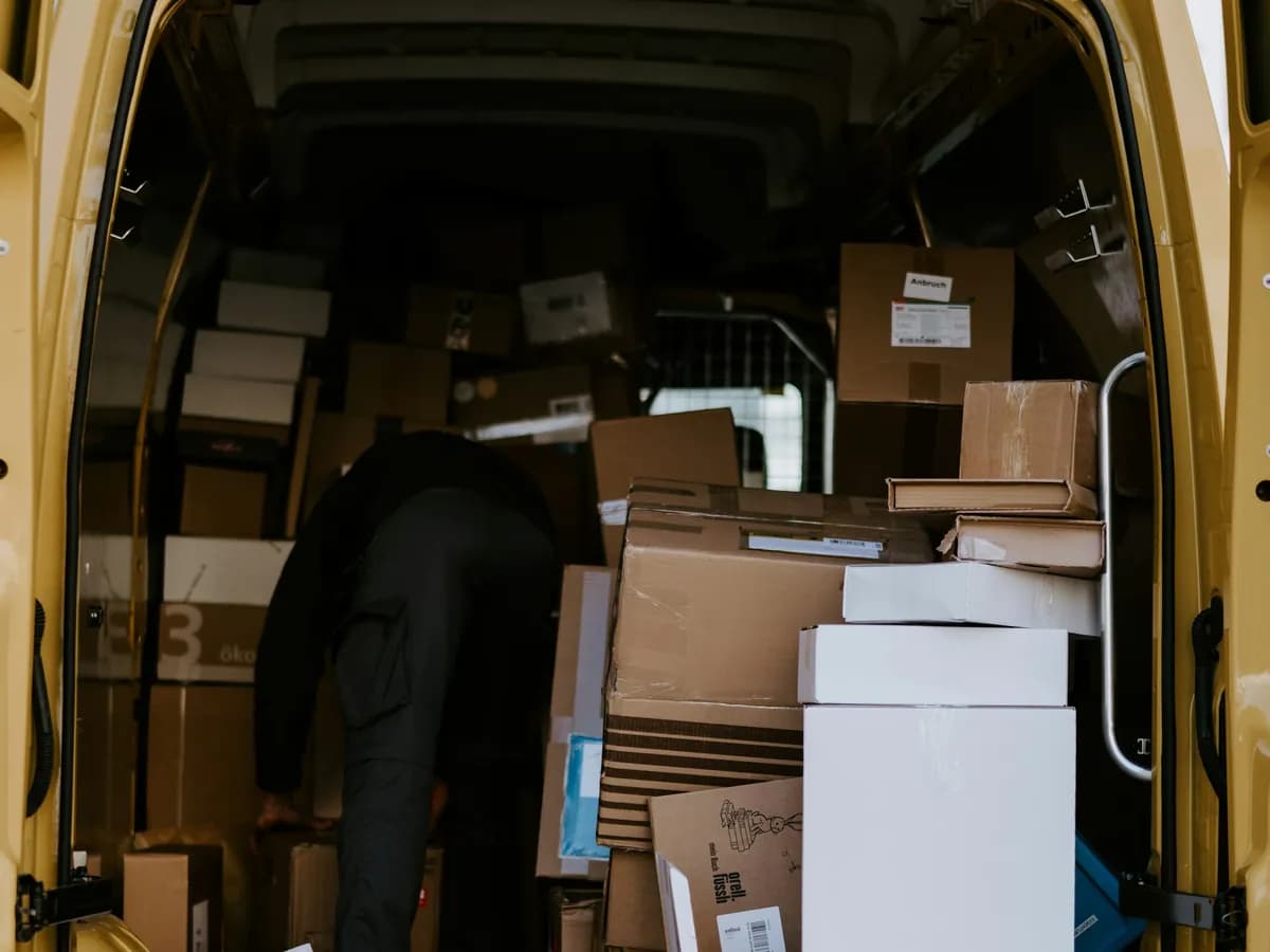 Courier loading parcels into the back of a delivery van